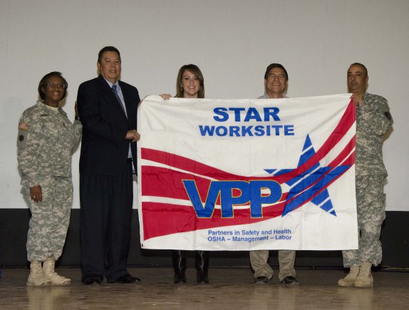 Image depicts a team proudly hoisting a VPP Star Site flag after receiving OSHA approval.